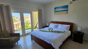 a bedroom with a bed and a chair and a balcony at Eagle Beach Cozy Condo in Palm-Eagle Beach +17 photos