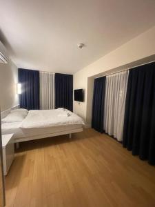 1 dormitorio con 1 cama y cortinas azules en Orbi city Panorama towers, en Batumi
