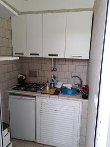 eine Küche mit weißen Schränken und einem Waschbecken in der Unterkunft casetta mariapia in Procida