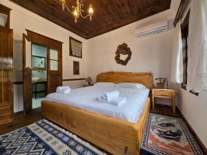 Un dormitorio con una gran cama de madera con sábanas blancas. en HOTEL ANSEL, en Berat