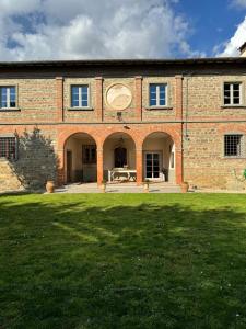 ein großes Backsteingebäude mit einem großen Rasenplatz in der Unterkunft Casale San Giorgio in Luco di Mugello