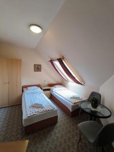 a room with two beds and a table and a window at Korona Panzió in Balatonberény