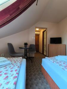 a room with two beds and a table and a tv at Korona Panzió in Balatonberény