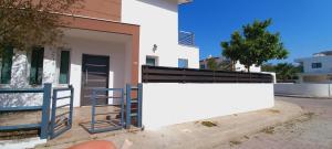 une maison avec un mur blanc et une clôture dans l'établissement 3 bedroom Villa in Pyla, à Larnaka