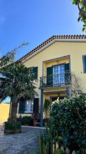 a yellow house with a balcony and a palm tree at Casa das Palmeiras in São Vicente Ferreira