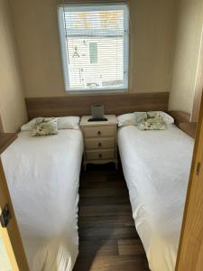 twee bedden in een kleine kamer met een raam bij Cleethorpes beach haven site in Cleethorpes