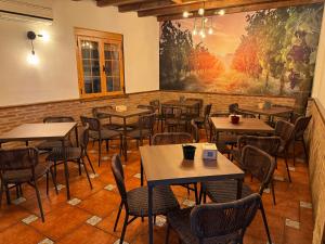 a restaurant with tables and chairs and a large painting on the wall at Hostal El Descanso Del Emperador in Jarandilla de la Vera