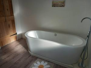 eine weiße Badewanne im Bad mit Holzboden in der Unterkunft Secluded Cornish farmhouse in Liskeard + 21 Fotos