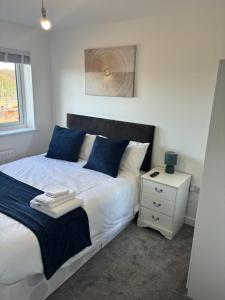a bedroom with a bed with blue pillows and a night stand at Foxglove Close in Middlesbrough