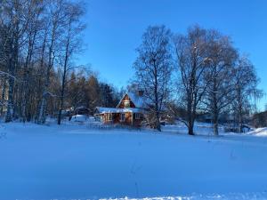 dom pokryty śniegiem przed polem w obiekcie Järvsöstugan w mieście Järvsö