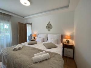 - une chambre avec un grand lit et des serviettes dans l'établissement Sunshine Homes Luxury Apartmanok, à Zamárdi