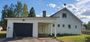 een grote witte garage met een grote garagedeur bij Villa Norrland, modern im skandinavischen Stil, mit Kamin, Garten und Saunafass in Vidsel