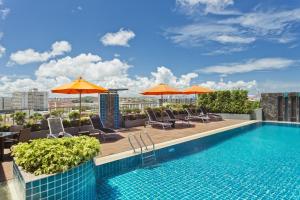 una piscina con sedie e ombrelloni in un edificio di Adelphi Pattaya - SHA Extra Plus a Centro di Pattaya