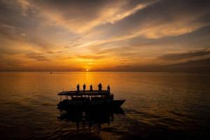 grupa ludzi na łodzi w wodzie o zachodzie słońca w obiekcie Morus Bliss - Divers' Preferred Hotel w mieście Maradhoofeydhoo