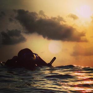 eine Person, die mit einem Paddel im Wasser liegt in der Unterkunft Morus Bliss - Divers' Preferred Hotel in Maradhoofeydhoo