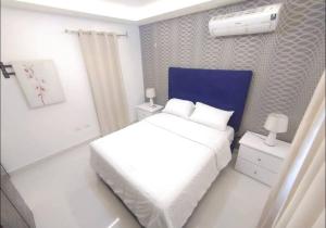 ein weißes Schlafzimmer mit einem weißen Bett und einem blauen Kopfteil in der Unterkunft Penthouse familiar in Santo Domingo