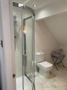 a bathroom with a toilet and a glass shower at The Cruck Barn, cosy rural escape near The Peak District in Matlock
