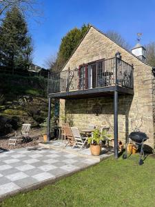 a patio with a deck and a grill and a house at The Cruck Barn, cosy rural escape near The Peak District in Matlock