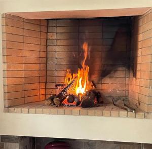 a brick fireplace with a fire in it at Garden Ηouse N°3 in Plomarion