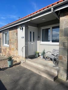 a house with a bench in front of it at Kinneuchar Cottage - by Elie, Dog Friendly. in Kilconquhar