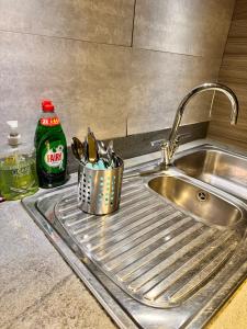 a kitchen sink with a metal basket of utensils at Luxury rooms in canary wharf in London
