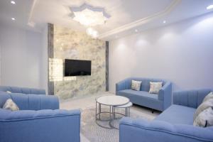 uma sala de estar com sofás azuis e uma televisão em أجنحة لفيف 1 em Al Madinah