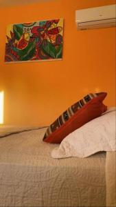 a bedroom with a bed with an orange wall at Hostel Avetaia in Santa Rosa de Calamuchita