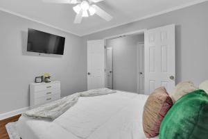 a white bedroom with a bed and a flat screen tv at GoodLiving: Serenity in Atlanta
