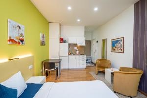 a bedroom with a bed and a kitchen with a table at Kalanj Apartmani I Sobe in Belgrade