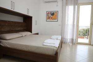 een slaapkamer met een bed met witte lakens en een raam bij Square View Apartment in Vlorë