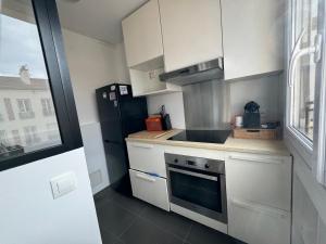 uma cozinha com armários brancos e um frigorífico preto em Vitry em Vitry-sur-Seine