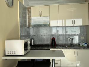 a kitchen counter with a microwave and a sink at Magnific flat Copacabana with ocean view in Playa de las Americas