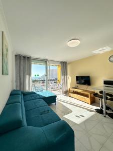 sala de estar con sofá azul y TV en Magnific flat Copacabana with ocean view, en Playa de las Américas