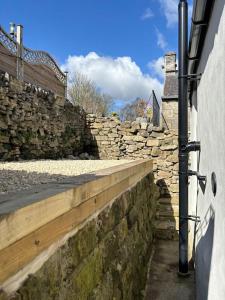 a stone retaining wall next to a building at Homestead Cottage in Bradwell
