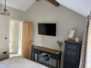 a bedroom with a desk and a tv on the wall at Homestead Cottage in Bradwell