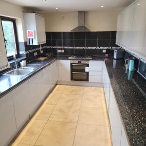 a kitchen with white cabinets and a tile floor at Modern 4 Bed House for 9 guests in Tilbury