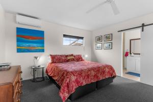 um quarto com uma cama com uma colcha vermelha em Moana Vista em One Tree Point