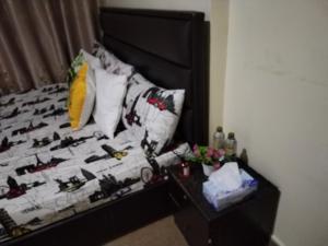 Una cama con cabecero negro y una mesa con flores en My Home Stay Apartment, en Abu Dabi