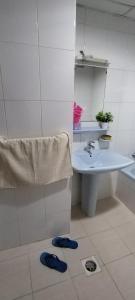 y baño con lavabo, espejo y zapatillas azules. en My Home Stay Apartment, en Abu Dabi