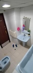 a bathroom with a toilet and a sink and a tub at My Home Stay Apartment in Abu Dhabi