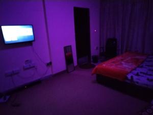 a purple room with a bed and a tv at My Home Stay Apartment in Abu Dhabi