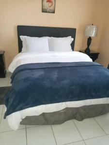 a bed with a blue and white blanket on it at Refreshed Modern Country Feel Apartment in Ocho Rios