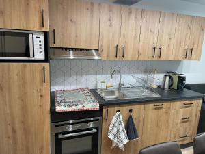 La cuisine est équipée d'une cuisinière, d'un évier et d'un four micro-ondes. dans l'établissement Appartement - Au cœur du Lac Blanc, à Orbey