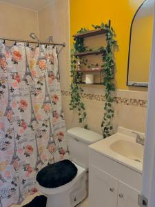 a bathroom with a toilet and a sink and a shower curtain at A little piece of home in Arverne