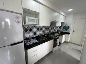 uma cozinha com armários brancos e um micro-ondas em M.APTO barra funda em São Paulo