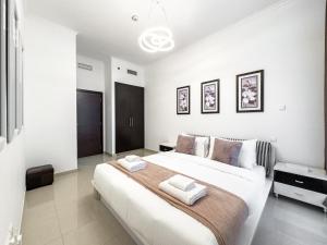 a white bedroom with a large bed with two towels at 2-BDR, Dubai Marina, Canal and city view in Dubai