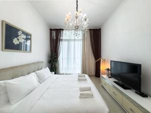 a white bedroom with a large bed and a television at 2-BDR, Dubai Marina, Canal and city view in Dubai