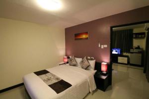 a bedroom with a bed with two lamps and a mirror at Leelawadee Modern Resort Huaykwang - ลีลาวดี ห้วยขวาง in Bangkok