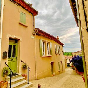 a yellow house with a green door and stairs at Chez Luis et David in Avignonet-de-Lauragais