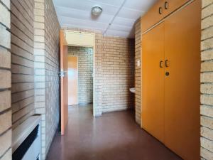 a hallway with orange doors and a brick wall at Orlando Hotel in Soweto